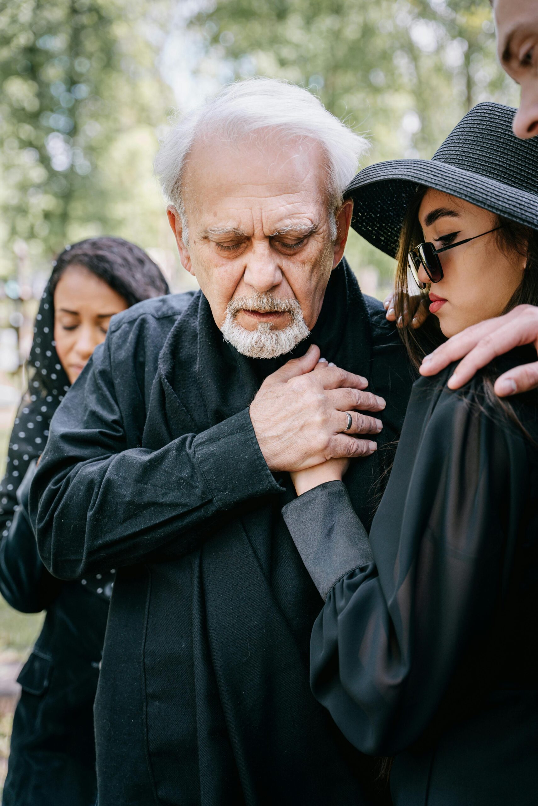 A sorrowful moment with mourners offering support at an outdoor funeral service.